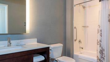 A bathroom with a white sink, mirror, and toilet, a shower with a glass door, and a bathtub.