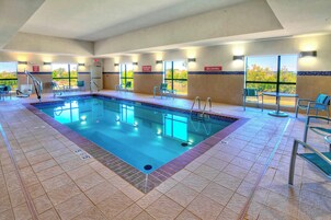 An indoor swimming pool with clear lane markings, a lifeguard chair, and a no diving sign.