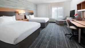 A hotel room with two beds, a desk, a chair, a TV, and a window with curtains.
