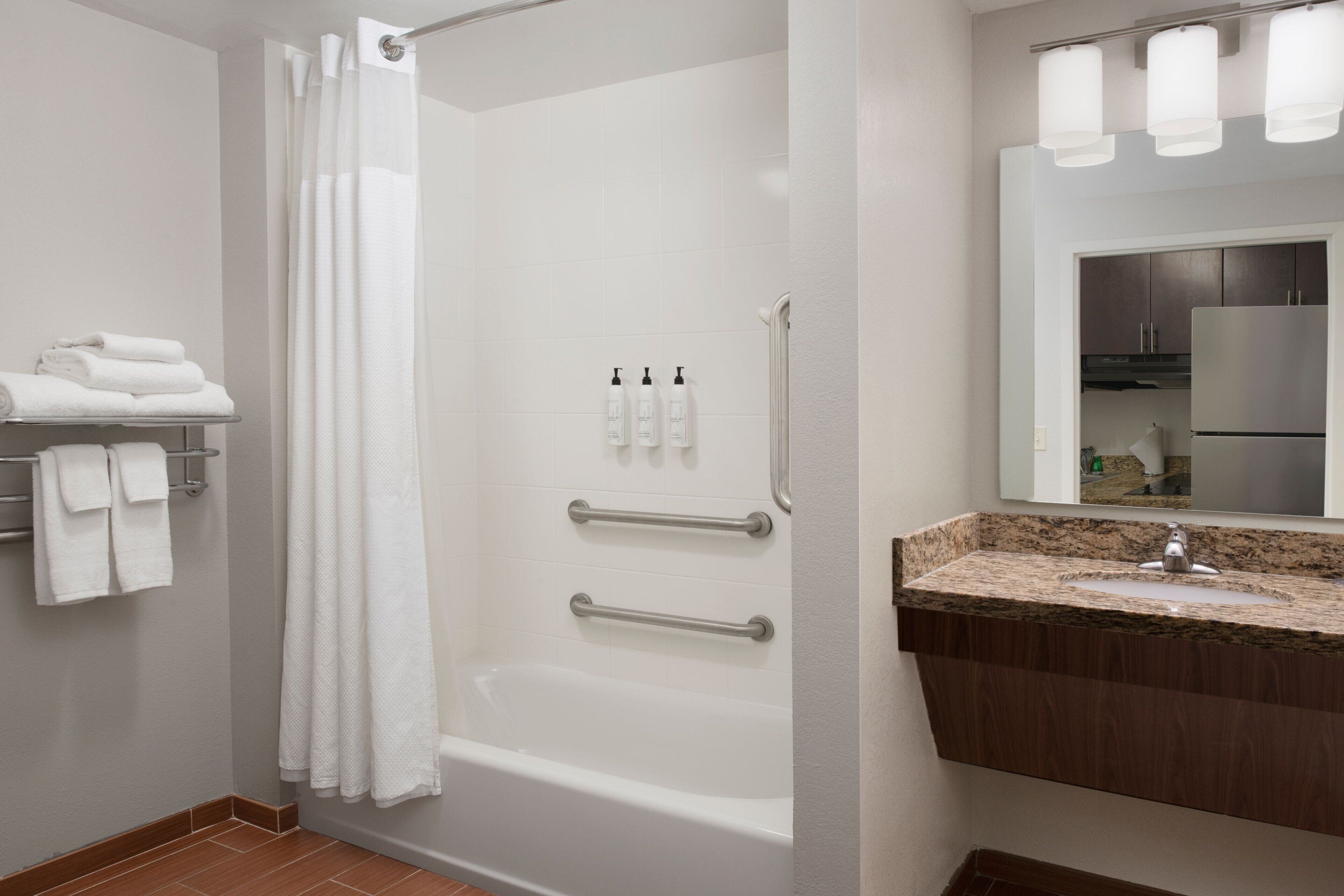 A bathroom with a shower, a sink, and a towel rack.