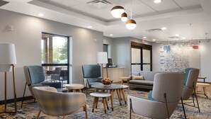 A modern lounge area with comfortable seating, a coffee table, and a large window providing natural light.