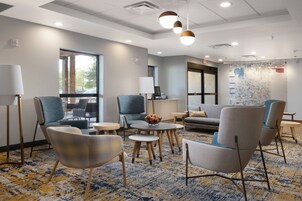 A modern lounge area with comfortable seating, a coffee table, and a large window providing natural light.