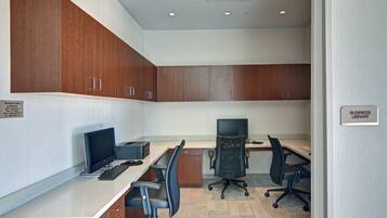 A modern office with two desks, two chairs, and wooden cabinets.