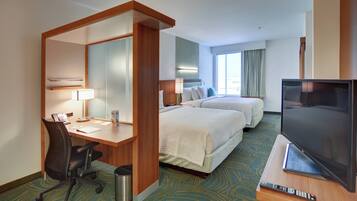 A hotel room with a desk, two beds, a TV, and a large mirror.