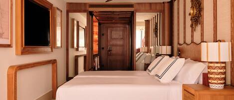 A hotel room with a large bed, a ceiling fan, a wooden door, and a mirror on the wall.