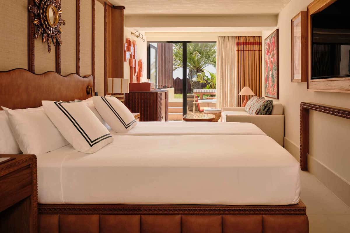 Ein Hotelzimmer mit einem großen Bett, einer Sitzecke, einem Schreibtisch und Blick ins Freie.