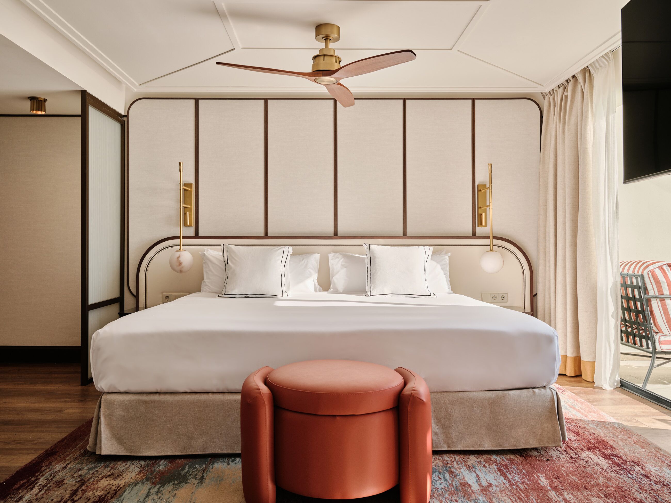 Habitación de hotel con una cama grande, un ventilador de techo, una mesita y vistas al exterior.