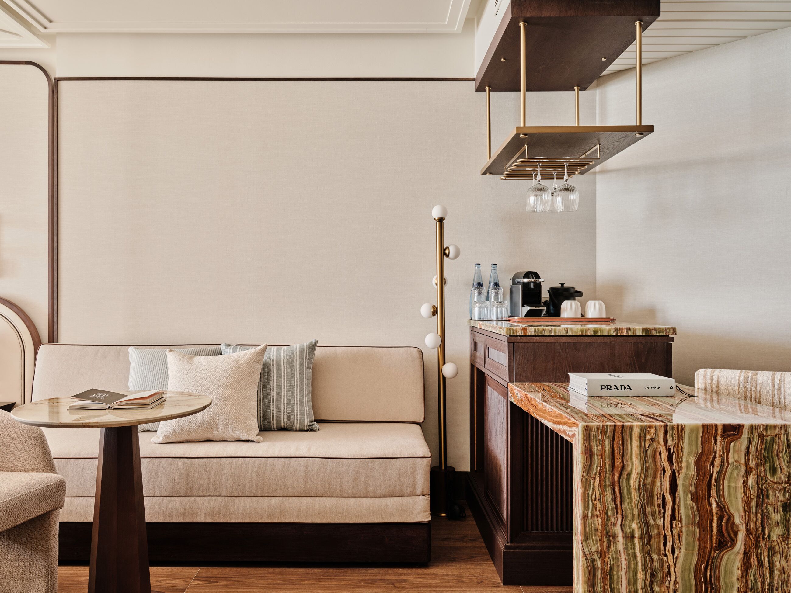 Una habitación de hotel moderna con sofá, una mesita redonda, un rincón de café y una encimera de mármol.