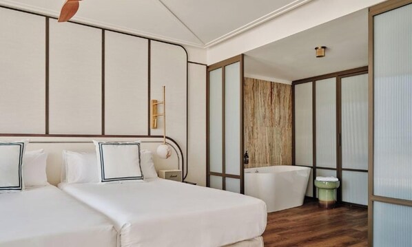 A hotel room with a large bed, a separate bathroom, and a wooden floor. - BLESS Ibiza The Site - Preferred Hotels & Resorts, Legend Collection (Sant Josep de sa Talaia)