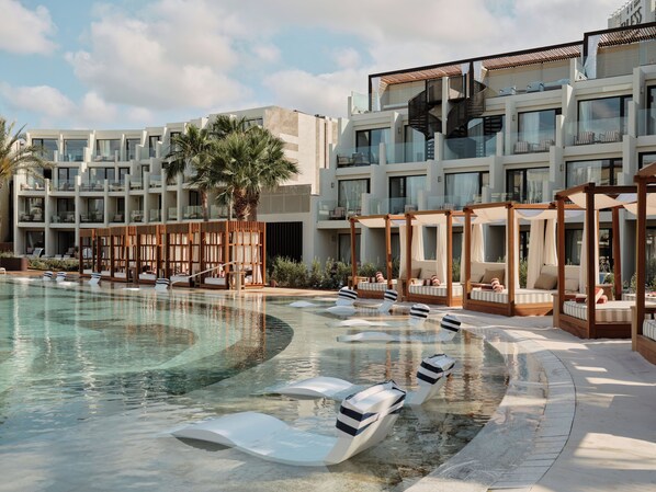 A modern hotel with a pool, sun loungers, and a covered seating area. - BLESS Ibiza The Site - New Opening 2026 (Sant Josep de sa Talaia)