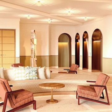 A spacious lobby with a sofa, two armchairs, a round table, and a decorative column.