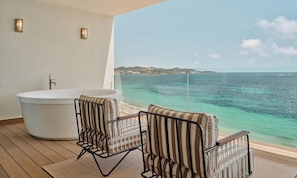 A balcony with a bathtub, two striped chairs, and a view of the sea. - BLESS Ibiza The Site - Preferred Hotels & Resorts, Legend Collection (Sant Josep de sa Talaia)