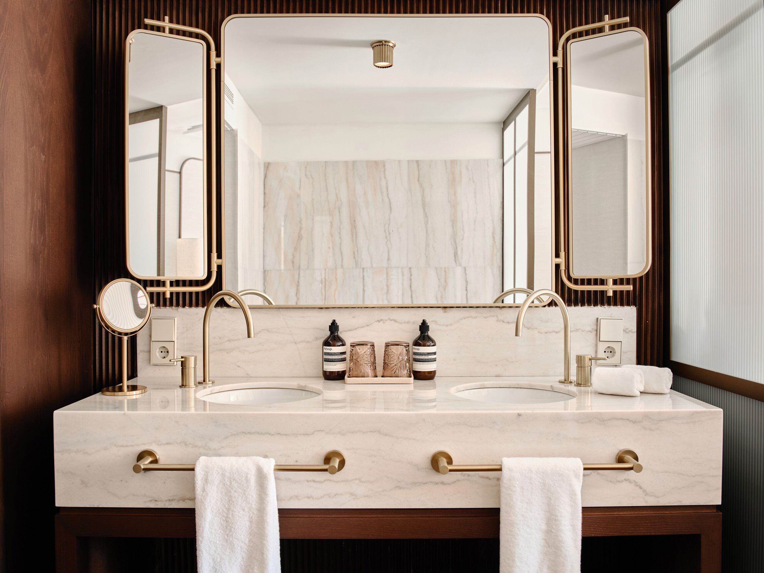 Une salle de bain avec deux lavabos, un grand miroir et un porte-serviettes.
