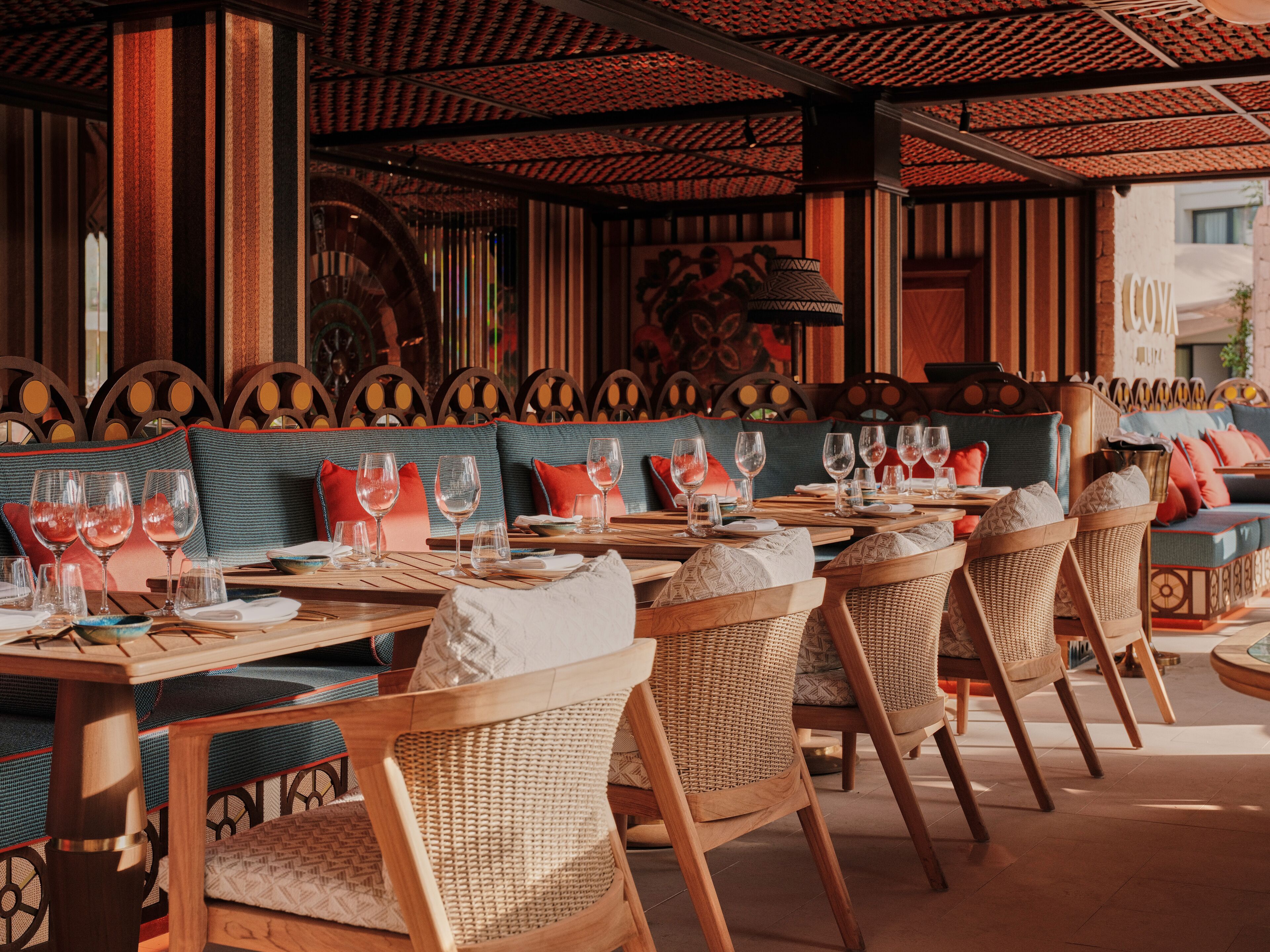 A restaurant with wooden furniture, a patterned ceiling, and a view of the street.
