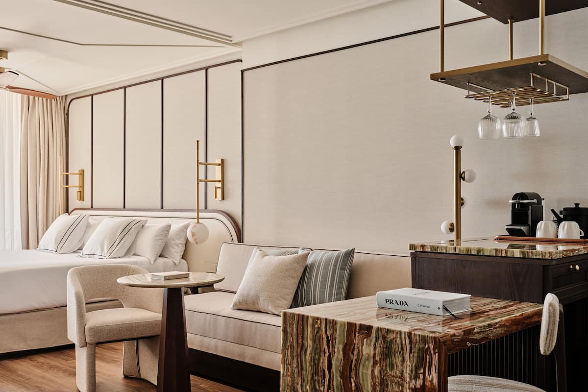 Ein modernes Hotelzimmer mit Bett, Sofa, rundem Tisch und einer Kaffeestation.
