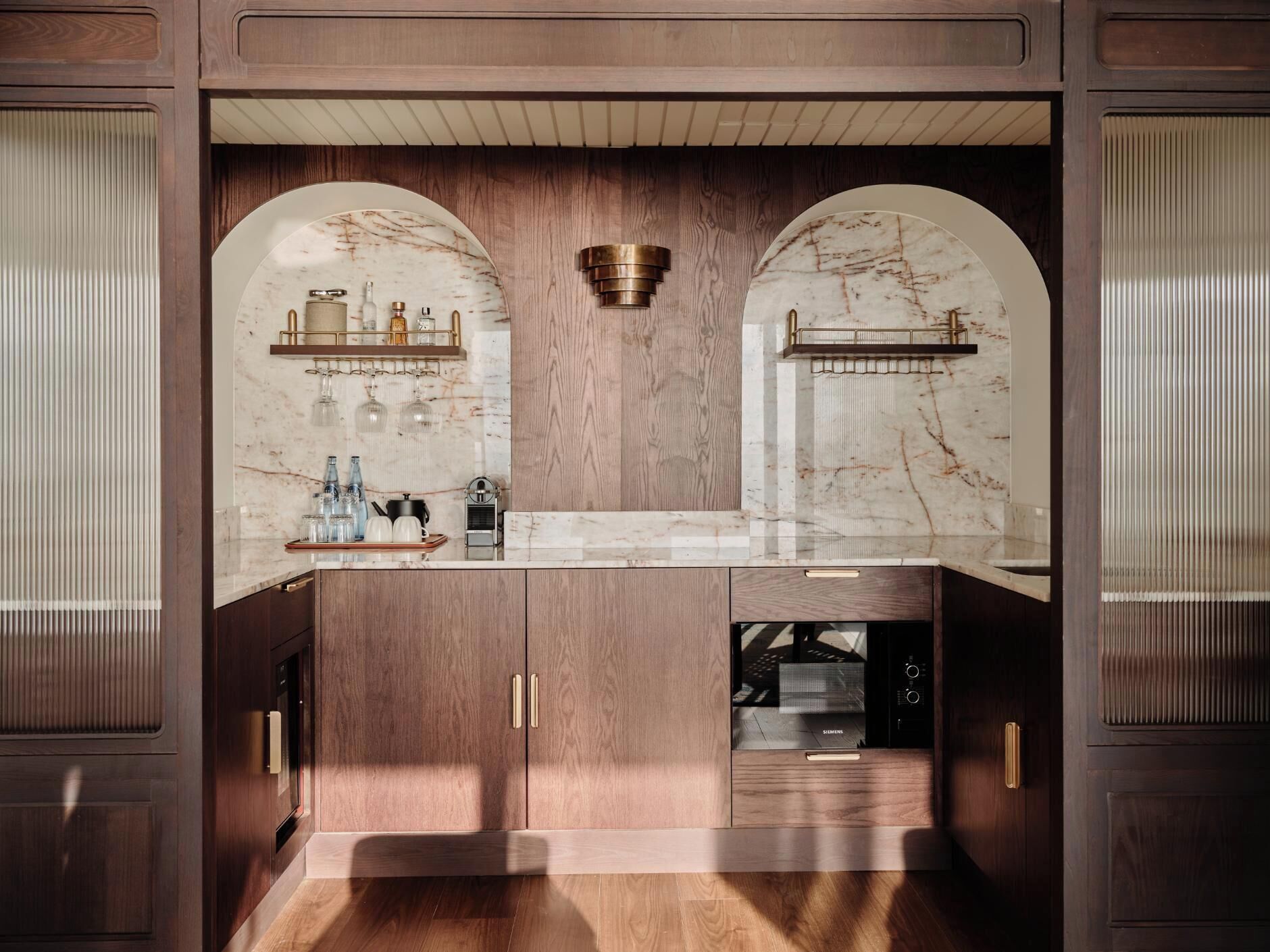 A kitchen with marble countertops, wooden cabinetry, and a built-in dishwasher.