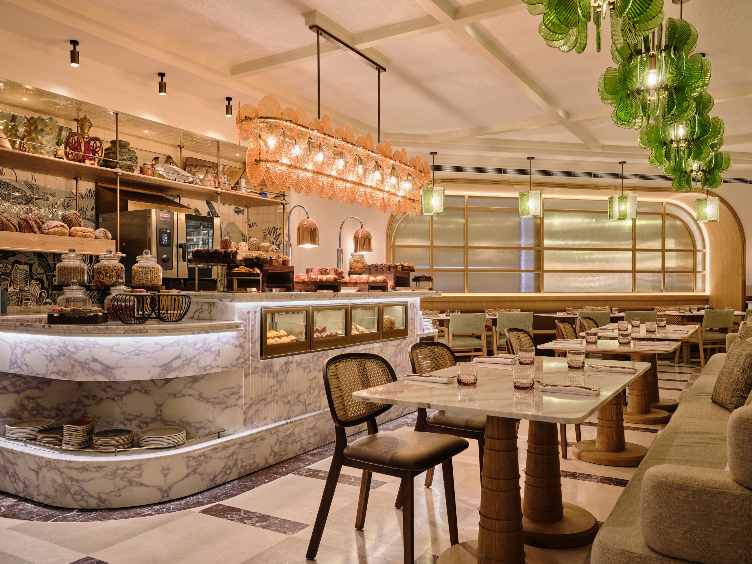 Ein Restaurantinneres mit Marmorarbeitsplatten, Glaskühlvitrinen und einer Sitzgegend mit Tischen und Stühlen.
