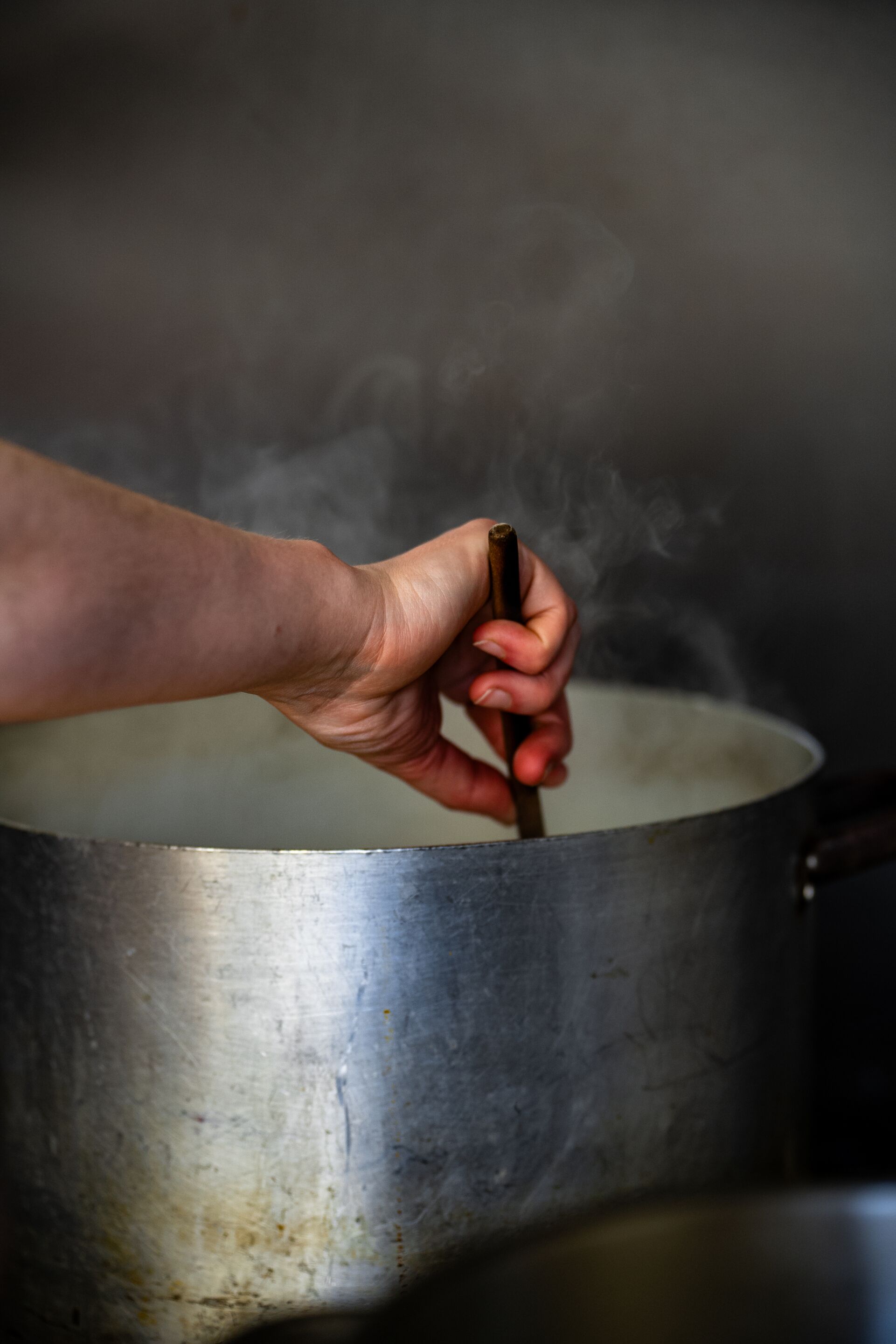 Een hand roert in een pan, er stijgt stoom op.