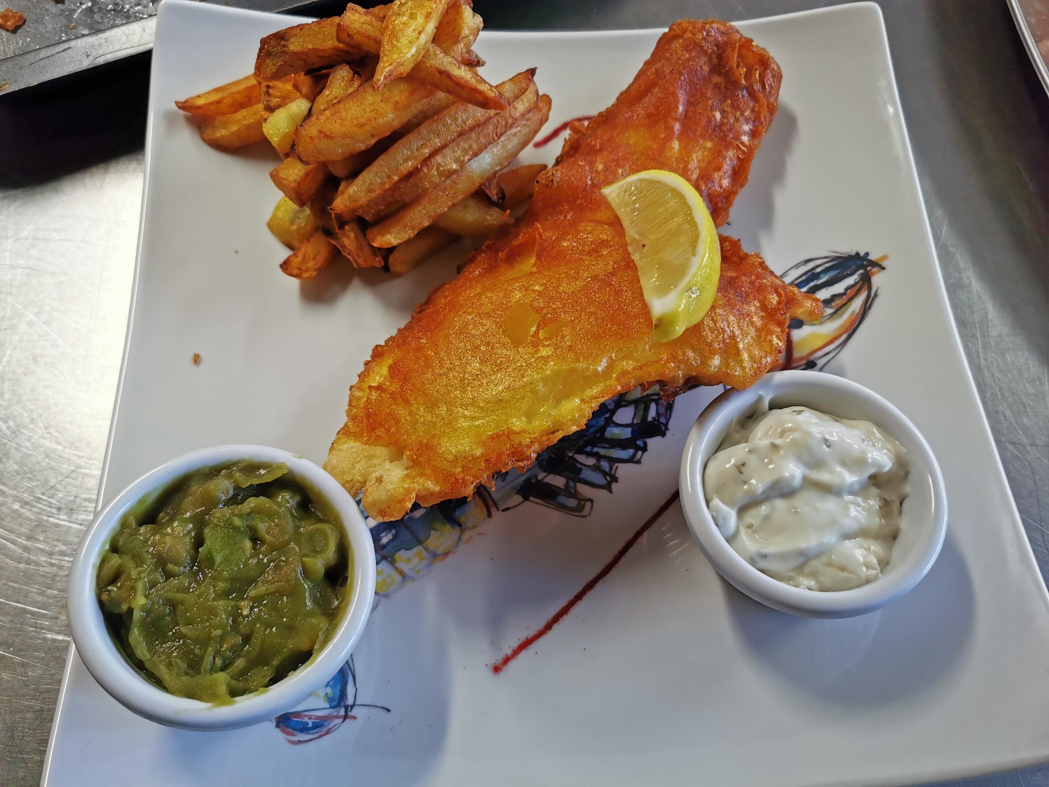 A plate with a fish fillet, chips, and two dips.