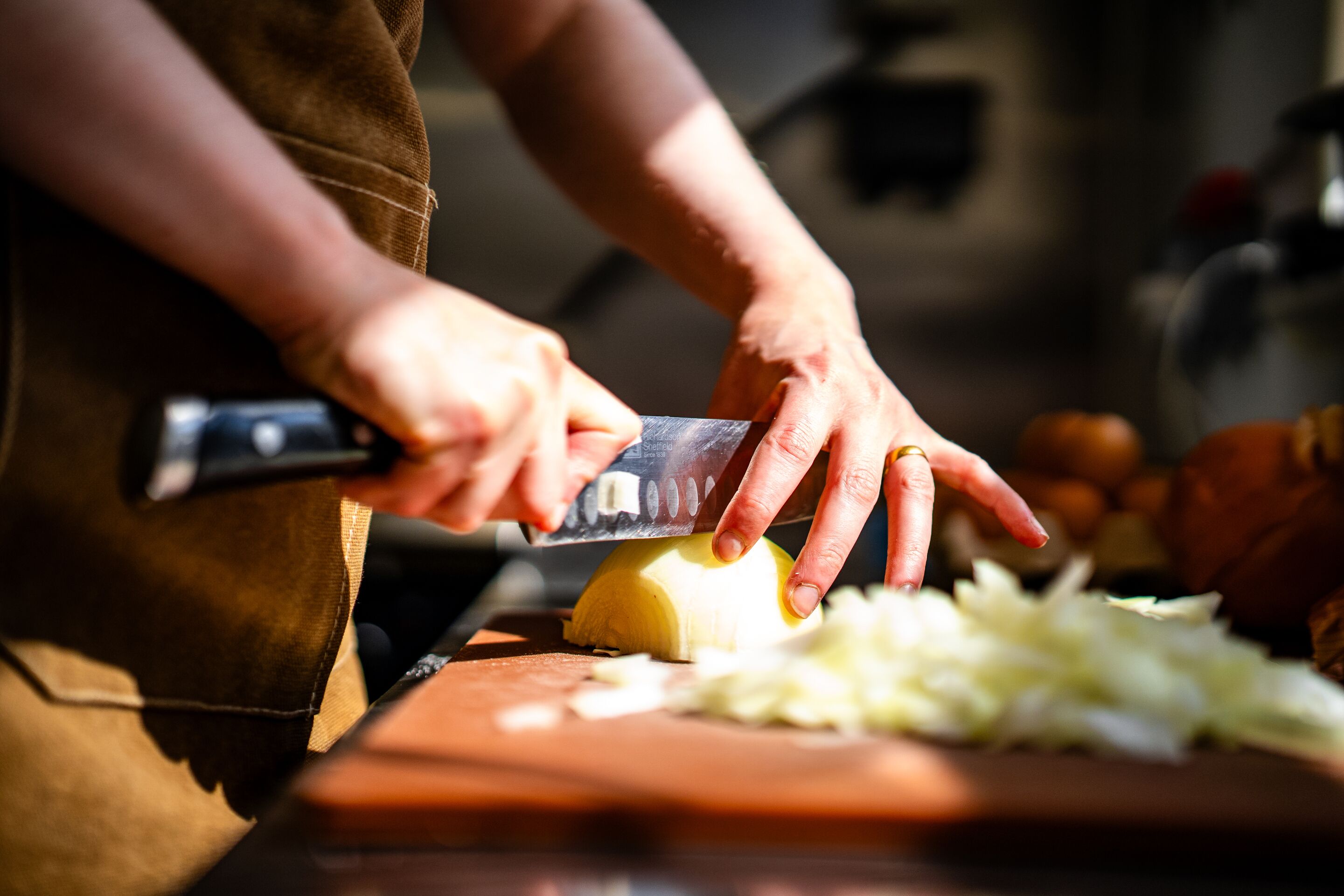 Una persona picando verduras con un cuchillo sobre una tabla de cortar.