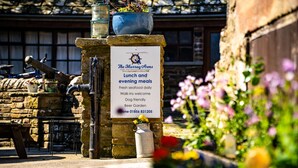 A stone pillar with a sign for The Murray Arms Hotel and Seafood Restaurant, offering lunch and evening meals, fresh seafood daily, walk-ins welcome, dog-friendly, and a beer garden.