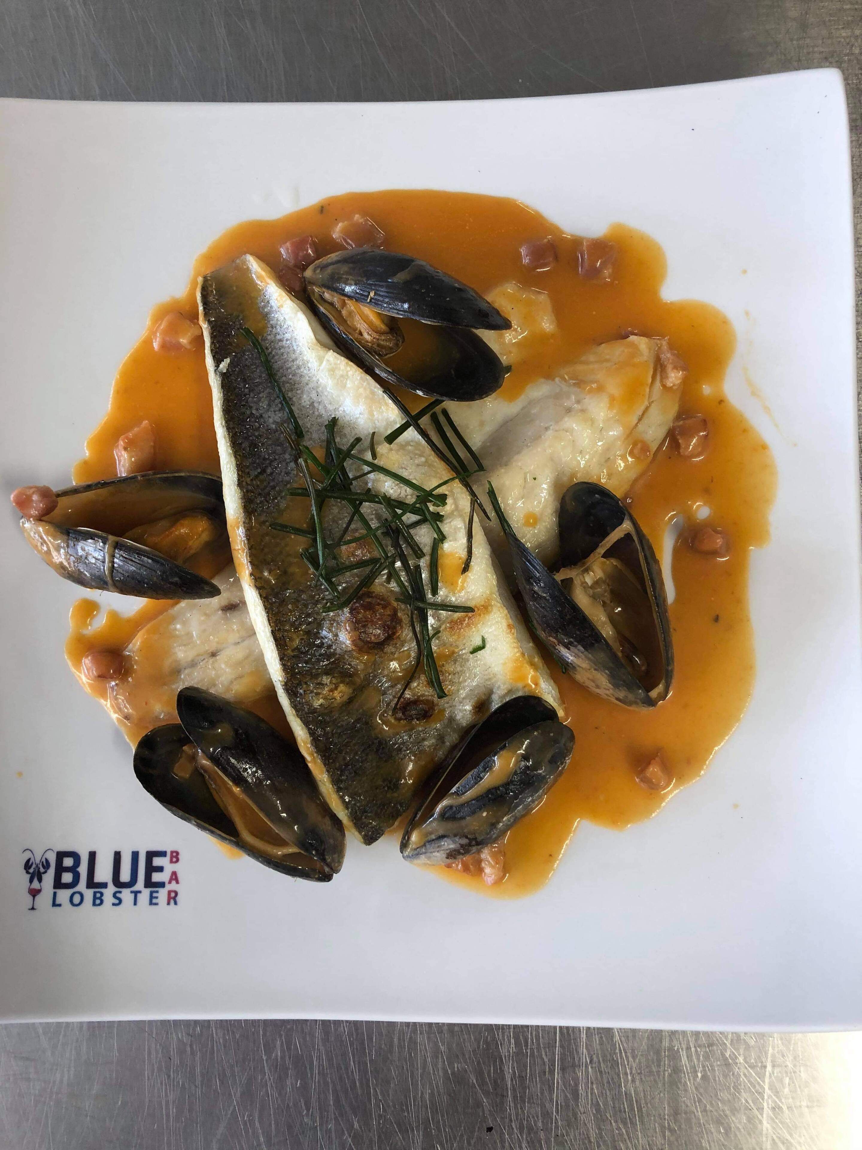 Un piatto di pesce con cozze e pesce su un piatto bianco.