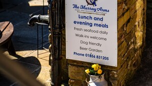 A stone structure with a sign for The Murray Arms Hotel and Seafood Restaurant, offering lunch and evening meals, fresh seafood, walk-ins, dog-friendly, and beer garden.
