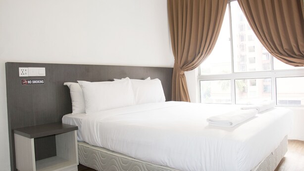 A hotel room with a bed, a nightstand, a "No Smoking" sign, and a window with curtains. - Promenade Service Apartments (Kota Kinabalu)