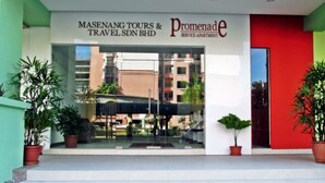 The facade of Masanang Tours & Travel SDN BHD with a red door and potted plants. - Promenade Service Apartments (Kota Kinabalu)