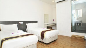 A hotel room with two beds, a bathroom with a glass shower, and a small sitting area. - Promenade Service Apartments (Kota Kinabalu)