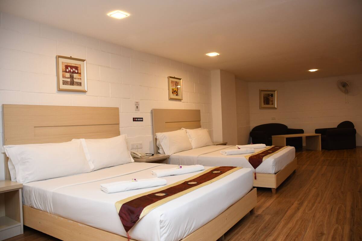 Une chambre d’hôtel avec deux lits simples, une tête de lit en bois, un petit bureau et une chaise.