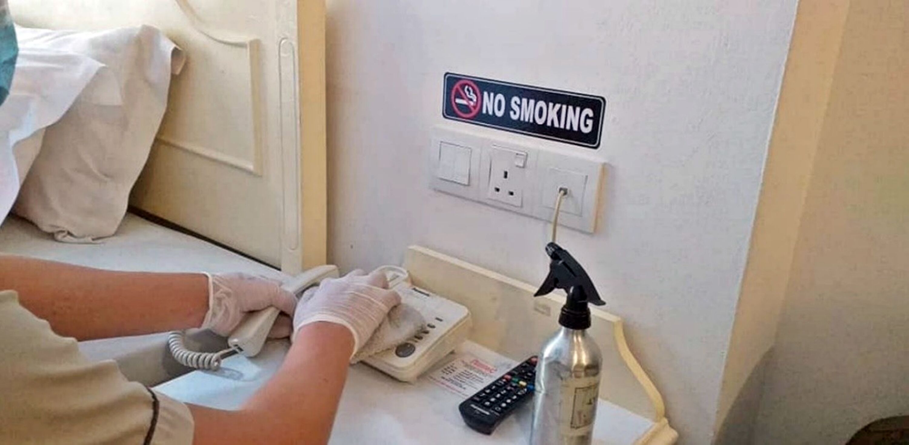 A person cleaning a room with a 'No Smoking' sign on the wall.