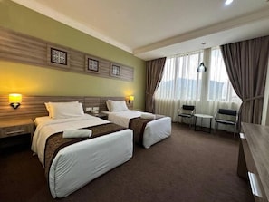 A hotel room with two beds, a desk, a chair, and a window with curtains. - HIG Hotel & Convention (Langkawi)