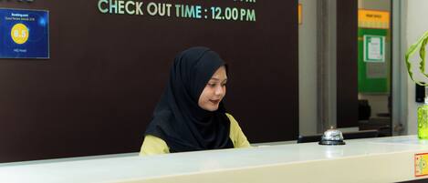 A reception desk with a sign indicating check-in time at 3:00 PM and check-out time at 12:00 PM.