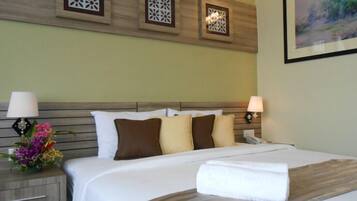 A hotel room with a bed, nightstands, lamps, decorative wall panels, and a framed picture.