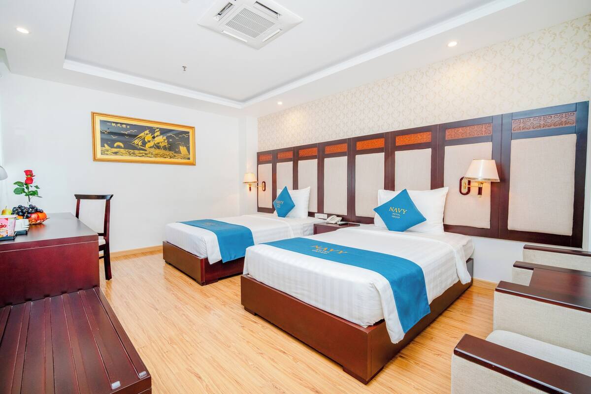 A hotel room with two beds, a desk, and a chair.