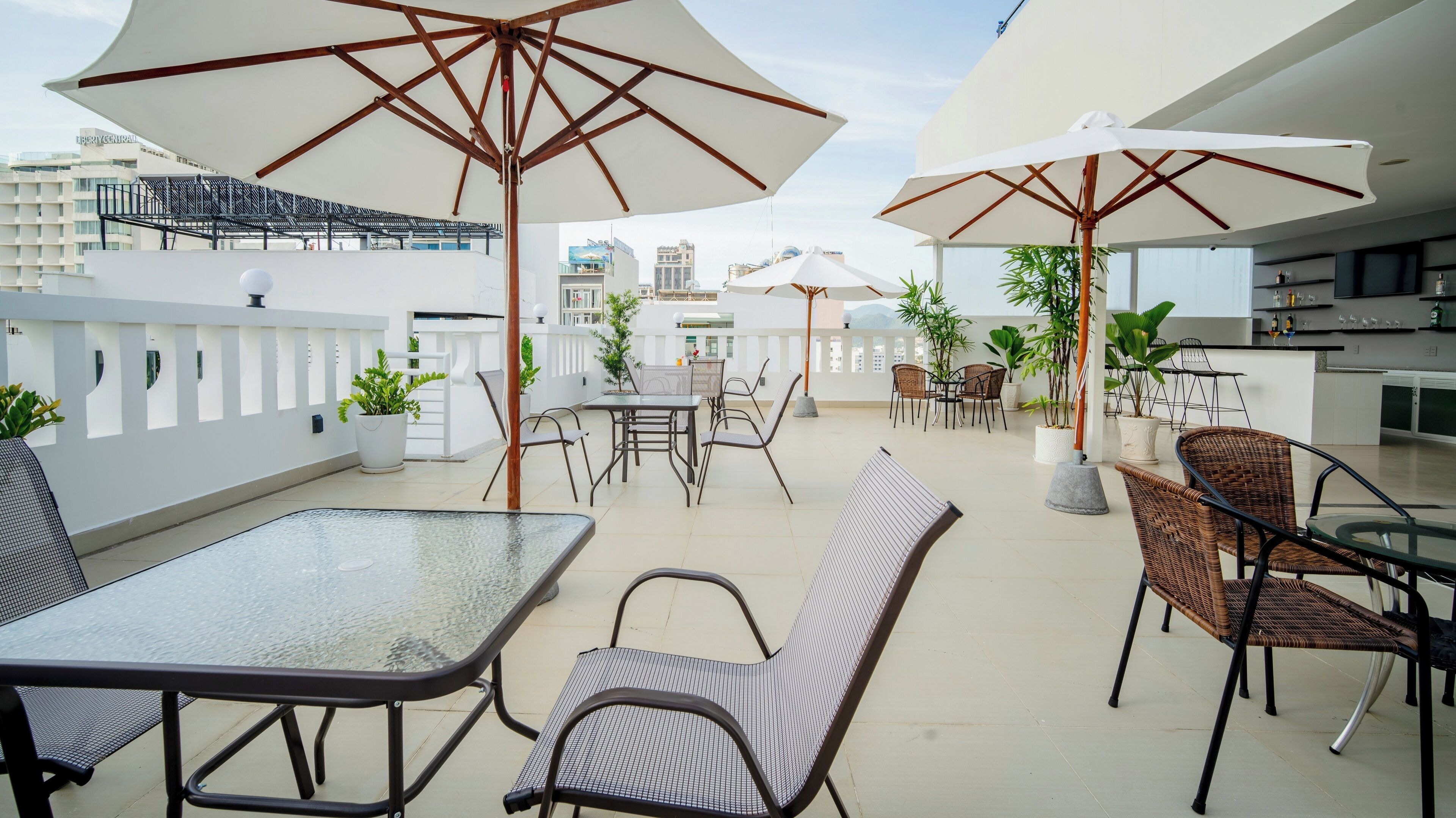 Une terrasse sur le toit, aménagée avec des espaces de détente en plein air, des parasols et des plantes en pot.
