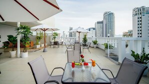 A rooftop terrace with outdoor seating, potted plants, and a city view. - Galliot Hotel Nha Trang (Nha Trang)