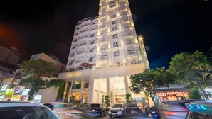 Un hotel de varios pisos con una entrada destacada y varias balcones.