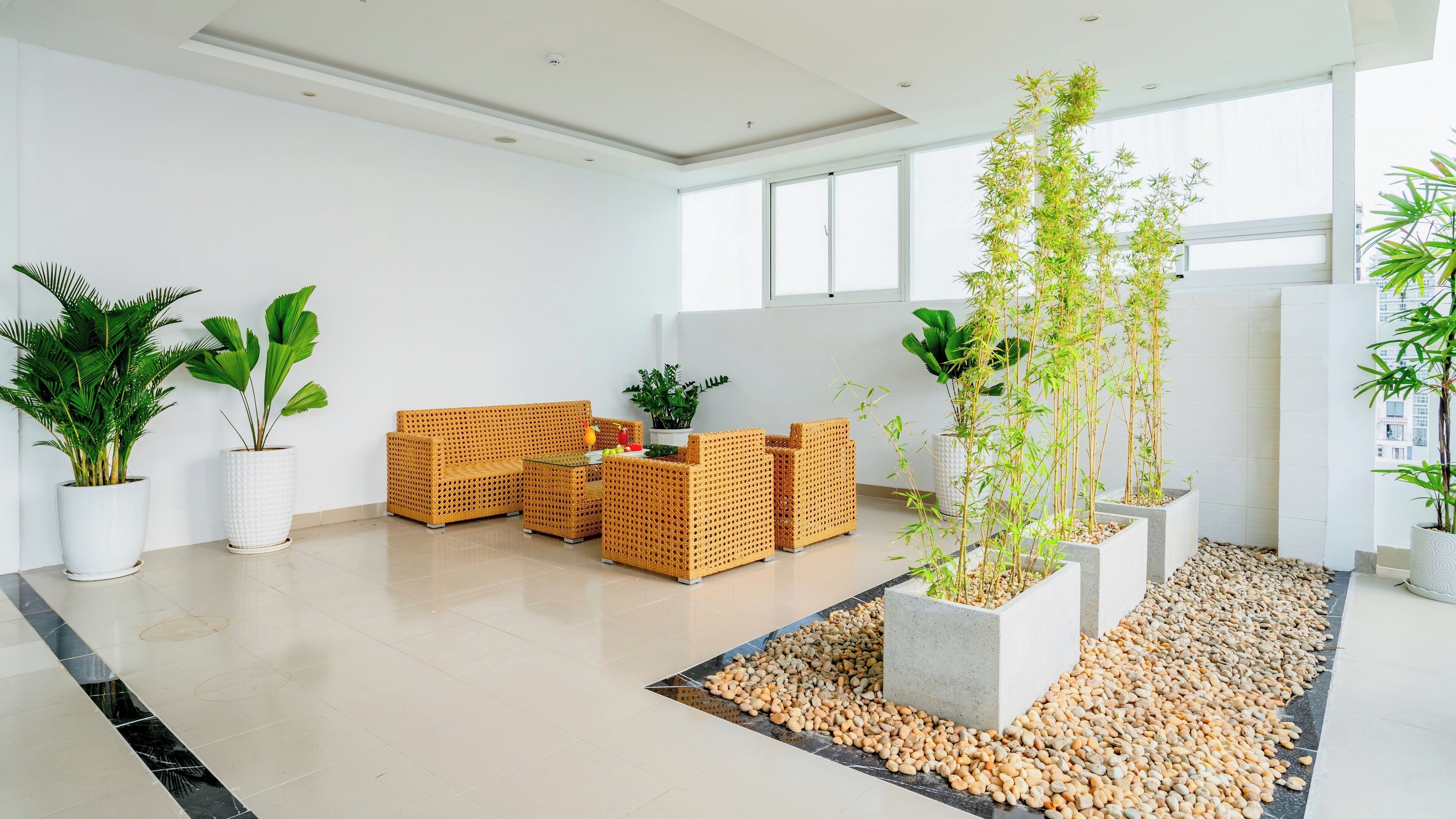 Een modern interieur met een zithoek, potplanten en een vloer van kleine kiezelstenen.