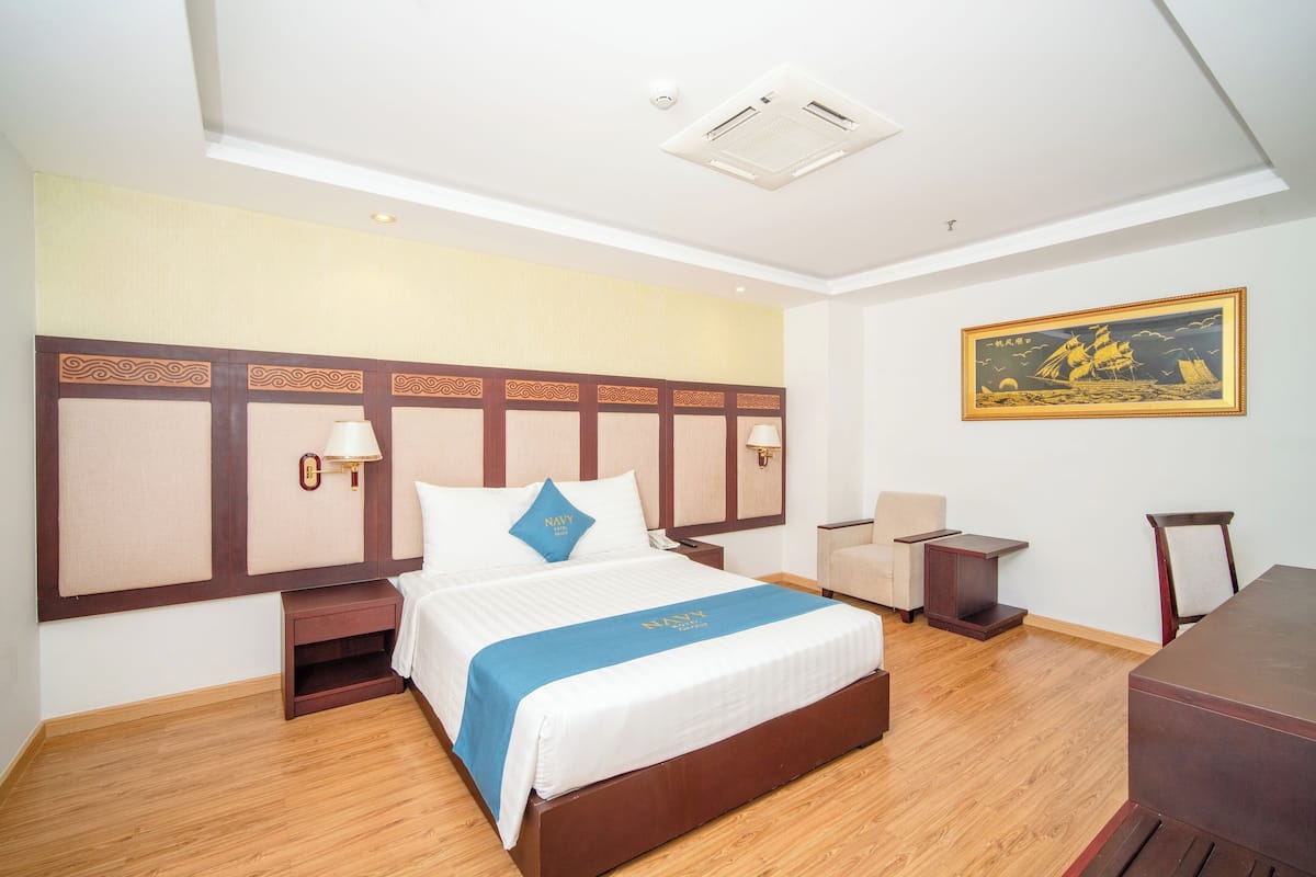 A hotel room with a large bed, bedside tables, a desk, and a chair.