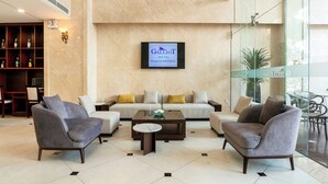 A hotel lobby with a sofa set, two armchairs, a coffee table, and a television displaying the hotel name. - Galliot Hotel Nha Trang (Nha Trang)
