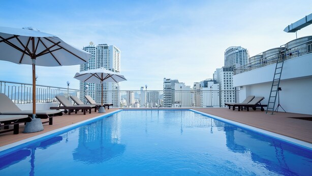 A rooftop pool with lounge chairs and umbrellas, surrounded by high-rise buildings. - Galliot Hotel Nha Trang (Nha Trang)