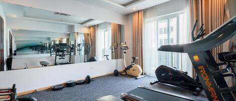 A hotel room with a treadmill, exercise equipment, and a large mirror.