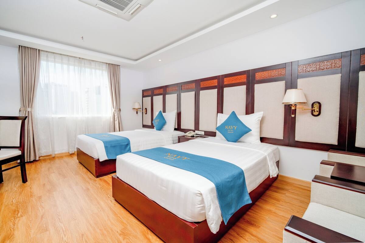A hotel room with two beds, a desk, and a chair.