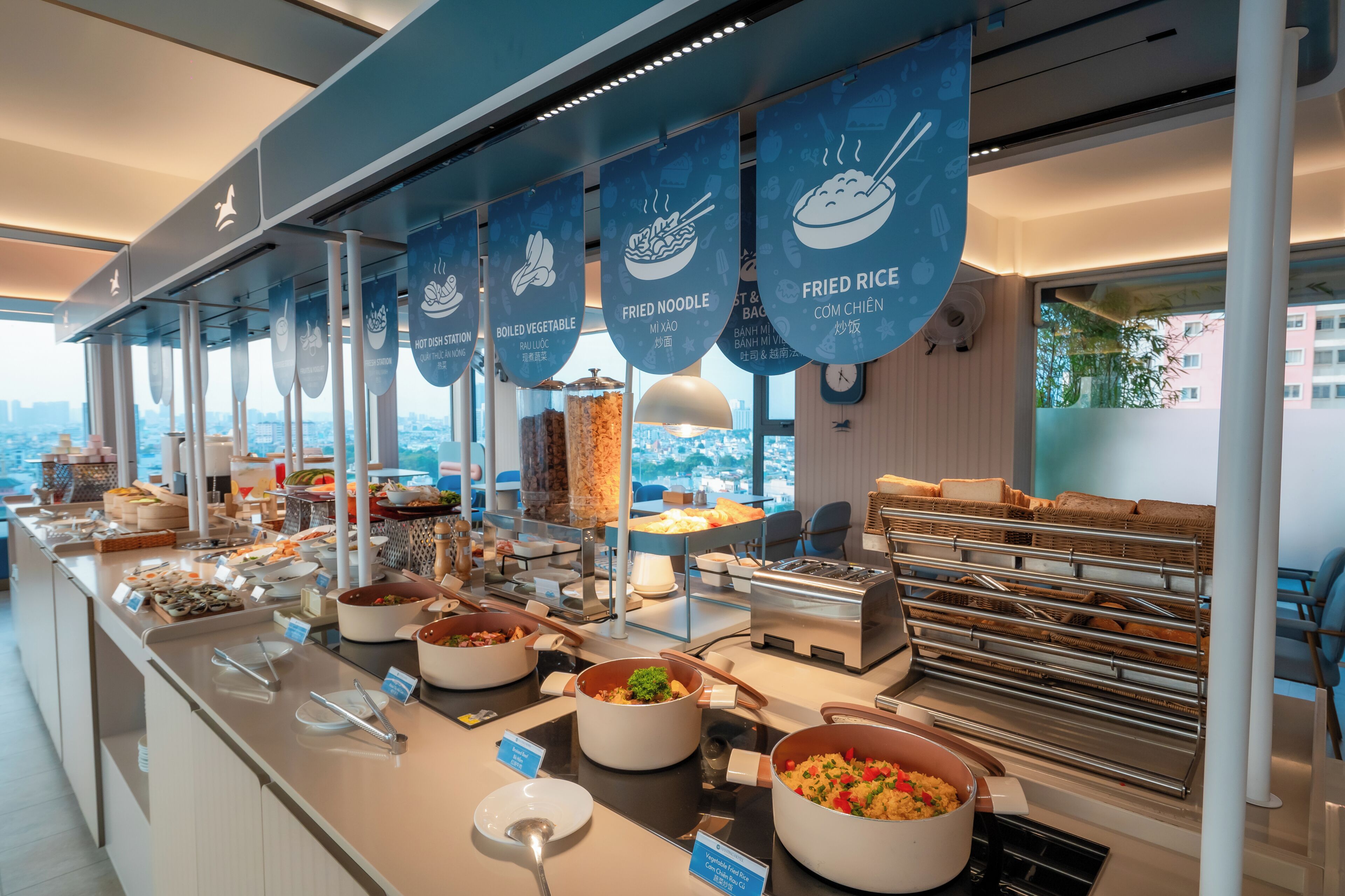 A buffet with various food options and a city view.