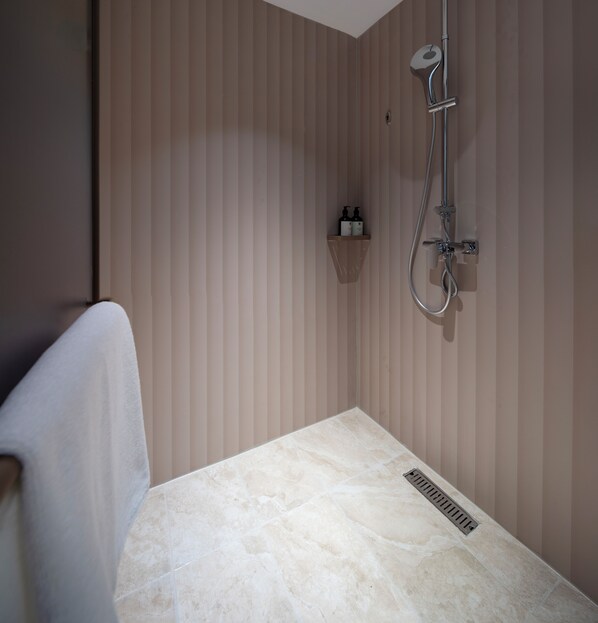 A bathroom with a shower, a towel rack, and a shelf with toiletries. - Hanting Hotel Ho Chi Minh City Downtown (汉庭国际胡志明市中心酒店) (Ho Chi Minh City)