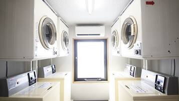 A laundry room with two washing machines, a dryer, and a window.