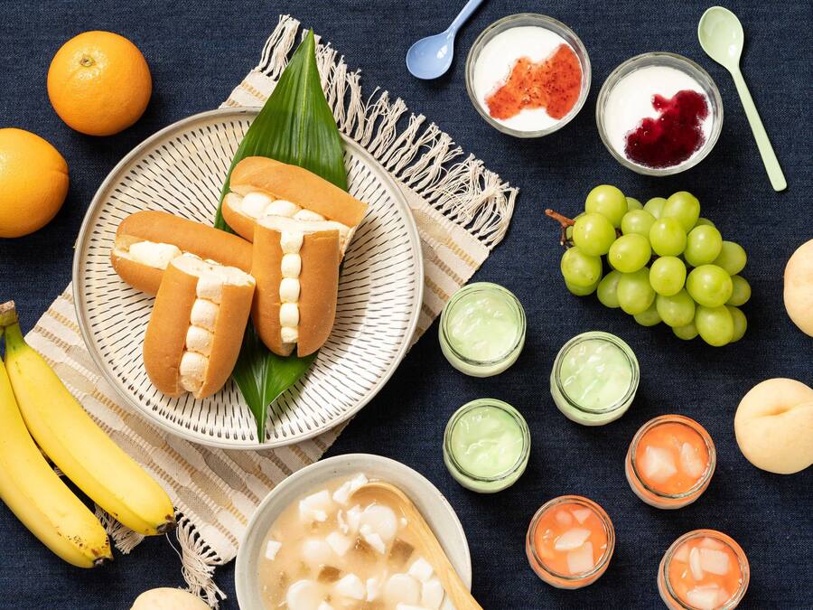 A table with various food items including bananas, grapes, and a bowl of soup.
