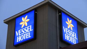 A building with two illuminated signs reading "Vessel Hotel".